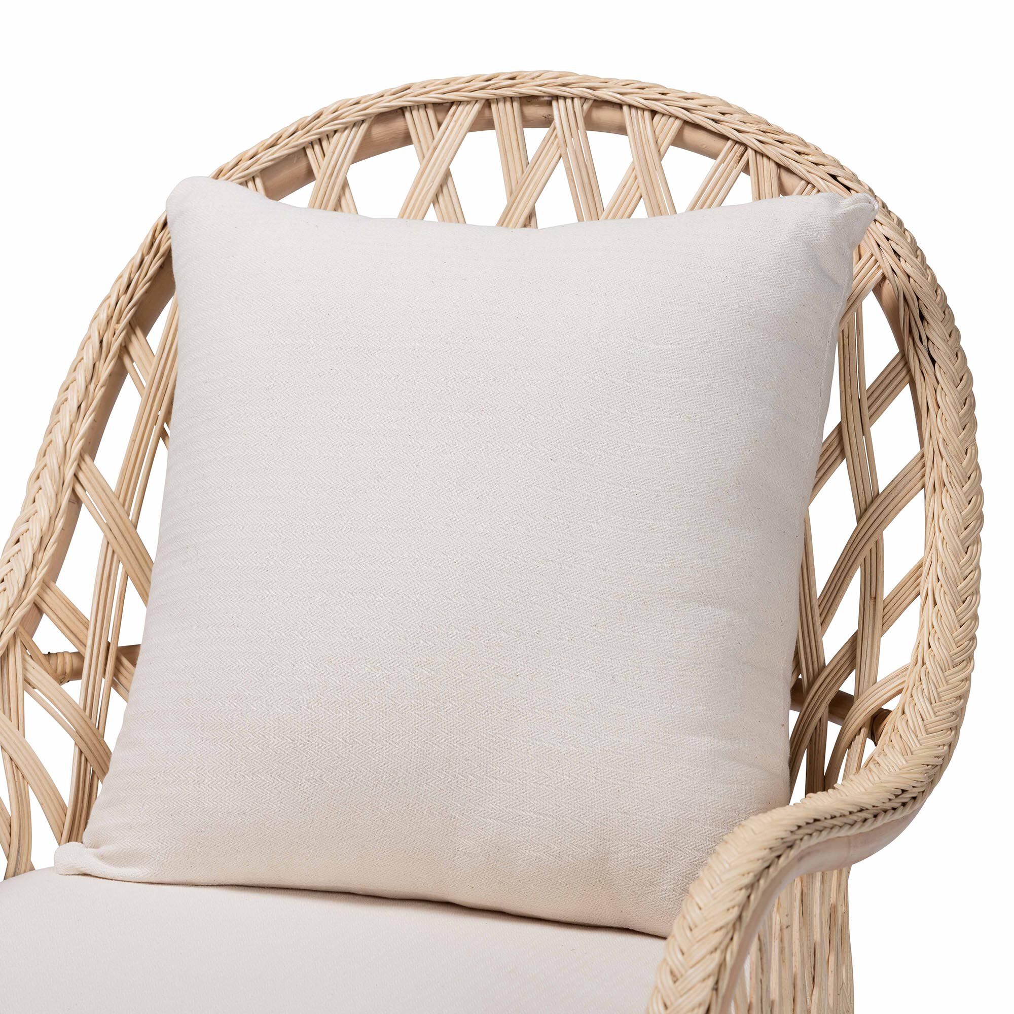 Close-up of white cushion on ivory braided rattan armchair