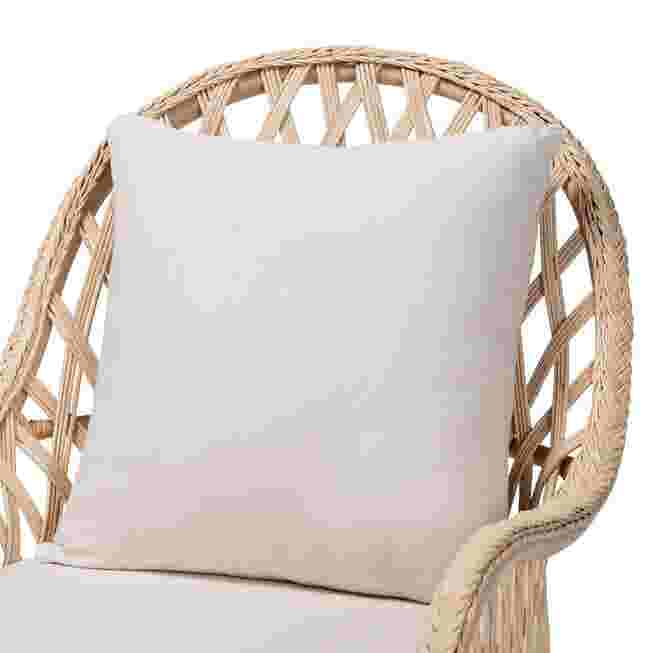 Close-up of white cushion on ivory braided rattan armchair