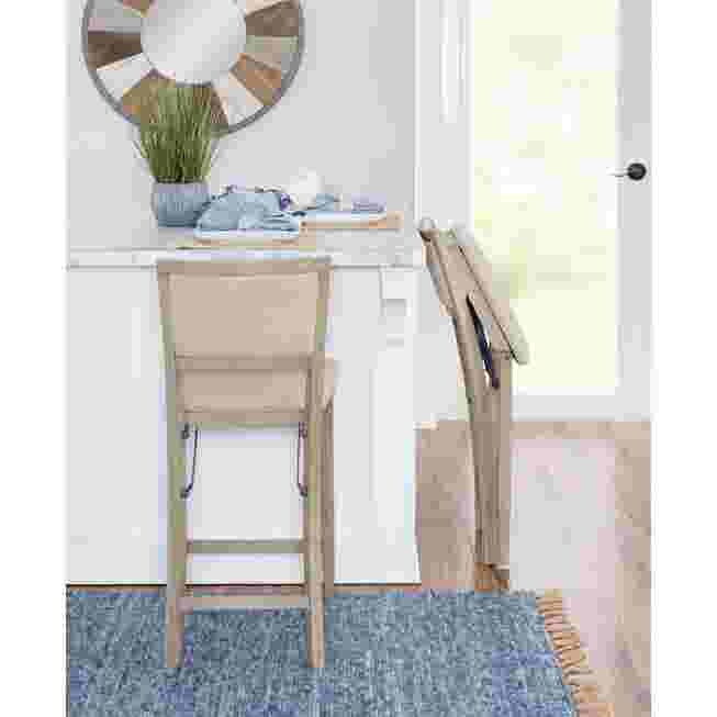 Grey wash folding stool in a kitchen setting with a person sitting on it