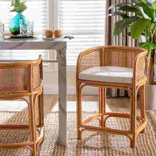Natural rattan counter-height stool with white cushion and curved armrest frame